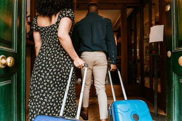 couple with suitcases walking into hotel